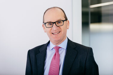 Man wearing glasses smiling at camera.